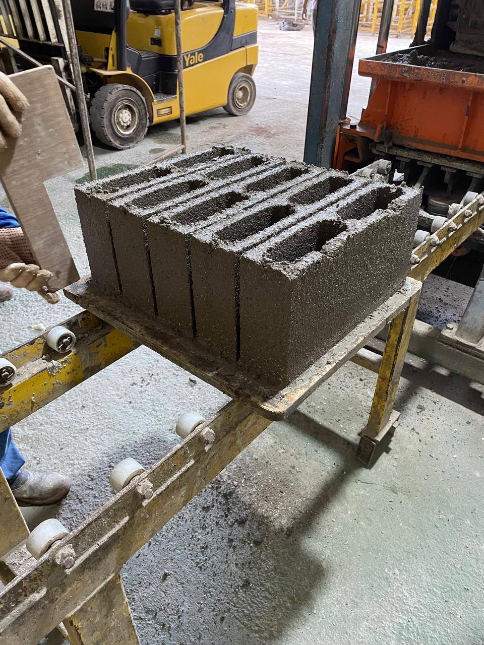 Bloco de concreto recém-prensado saindo na linha de produção da ComBlocos
